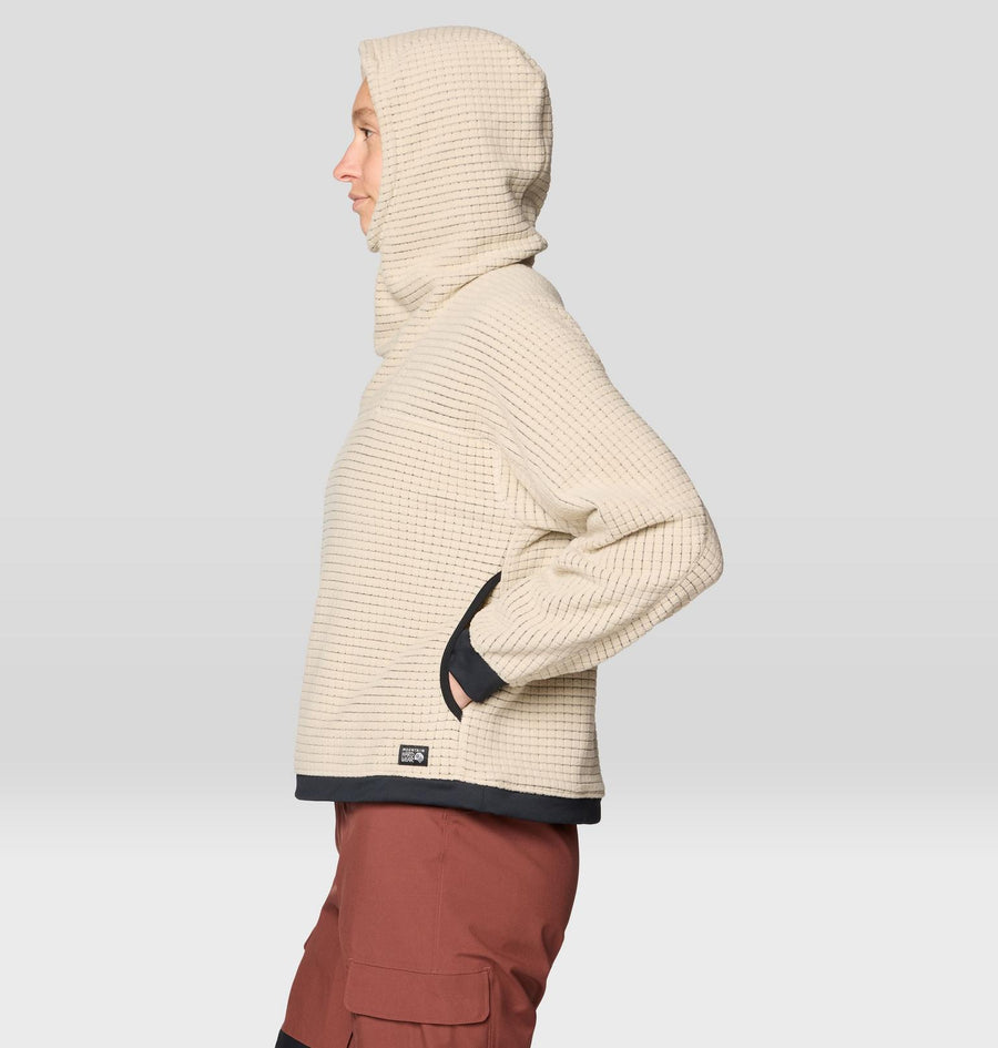 Person wearing a beige hooded jacket with a visible brand logo on a light gray background