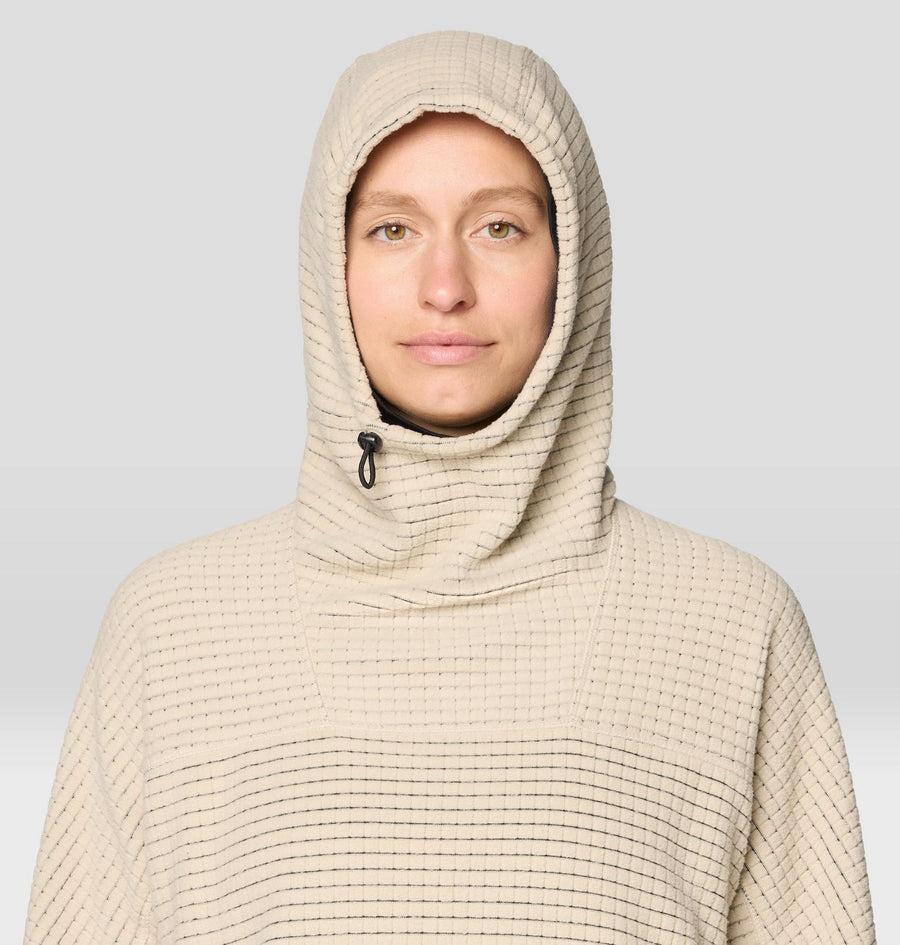 Person wearing a beige hooded garment against a plain background