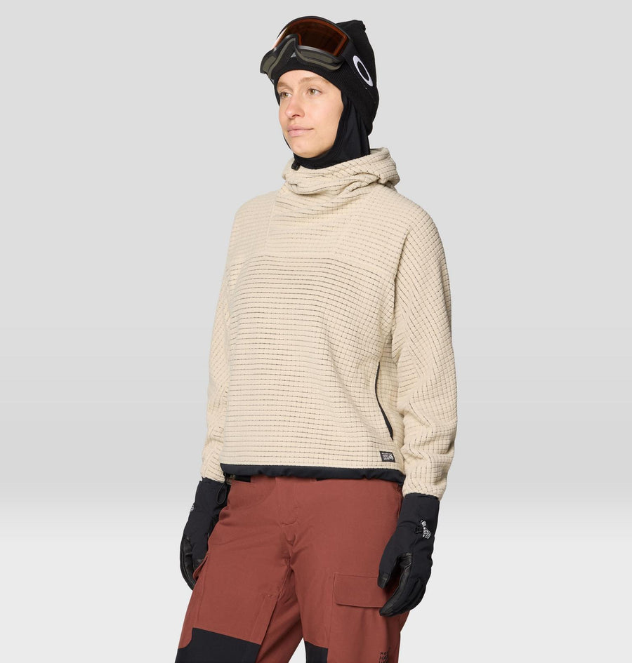 Person wearing a beige knit sweater, red pants, and black gloves on a light gray background