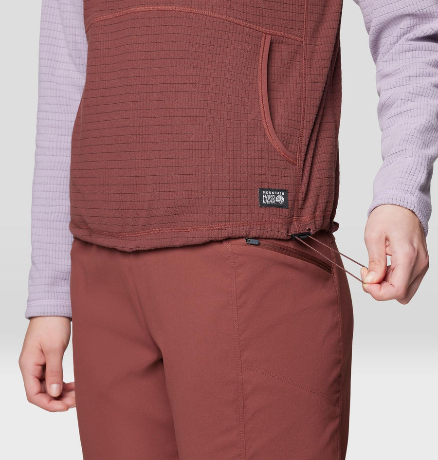 Person wearing a brown vest with a visible brand logo on a light gray background