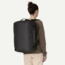 Person wearing an all black duffel bag like a backpack with Patagonia written on the side.