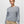 A person wearing a light grey sweater with khaki pants against a white background.