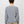 Back view of a person wearing a light grey sweater with khaki pants against a white background.