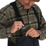 Man adjusting a black strap on Simms Challenger Insulated Bibs, wearing a plaid shirt and cap.