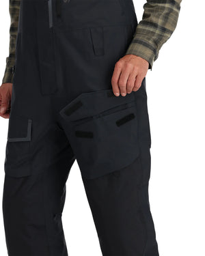 Black Simms Challenger Insulated bibs with multiple pockets worn by a person on a white background