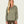 Person wearing a sage green long sleeve that buttons 1/4 of the way with brown pants.