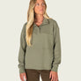 Person wearing a sage green long sleeve that buttons 1/4 of the way with brown pants.