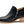 Black shoes with a silver zipper and a wooden heel against a white background.