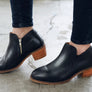 Person wearing a pair of black boots with a wooden heel.