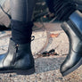 Person walking in a pair of black boots that have a zipper on the side.