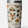 Tan cup with the Yeti logo and camping images all over it, in the colors green, orange and yellow against a white background.