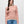 Person wearing a cream and orange striped sweater with blue jeans against a grey background.