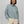 Person wearing a light blue sweatshirt with cream colored pants against a light grey background.